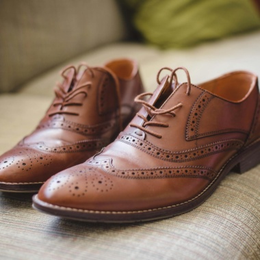 Elegant brown pair of leather shoes for men placed on gray surface at home