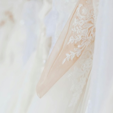 Stylish elegant white dresses hanging in wedding store against blurred background in daytime