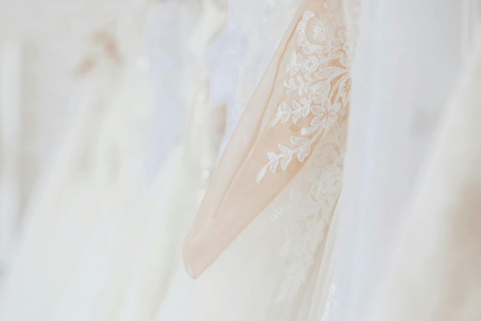 Stylish elegant white dresses hanging in wedding store against blurred background in daytime